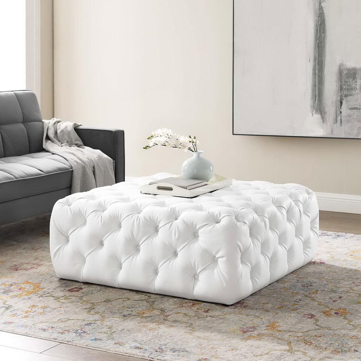 White tufted square ottoman styled as a chic coffee table in a modern living room || EEI-3773-WHI || front_angle_room