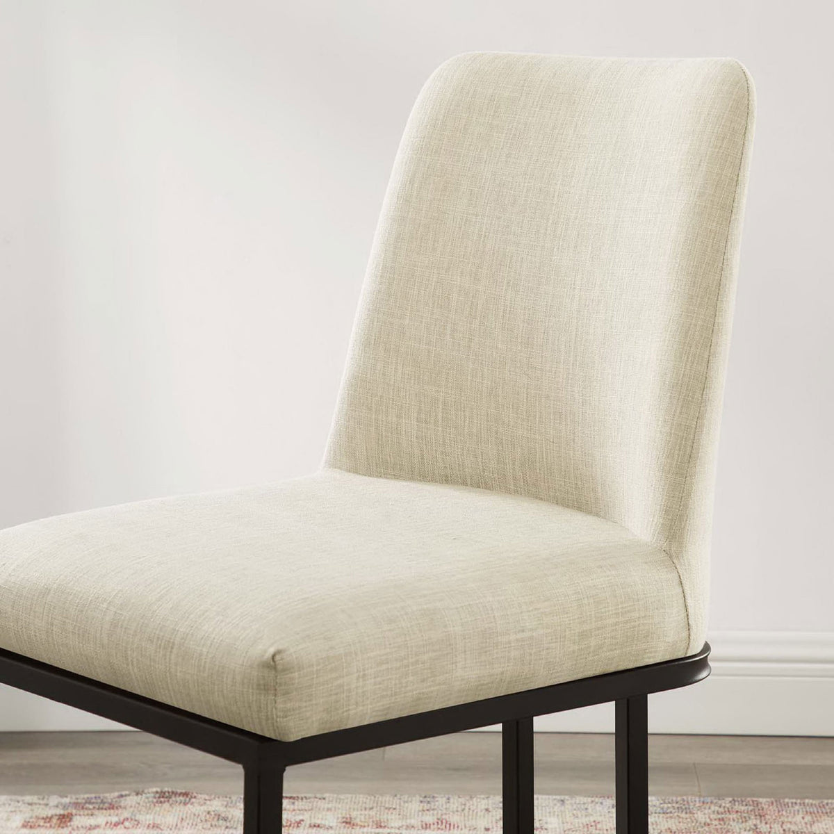 Beige fabric dining chair in a bright dining room showing softly curved back and smooth upholstery || EEI-3811-BLK-BEI || detail_room