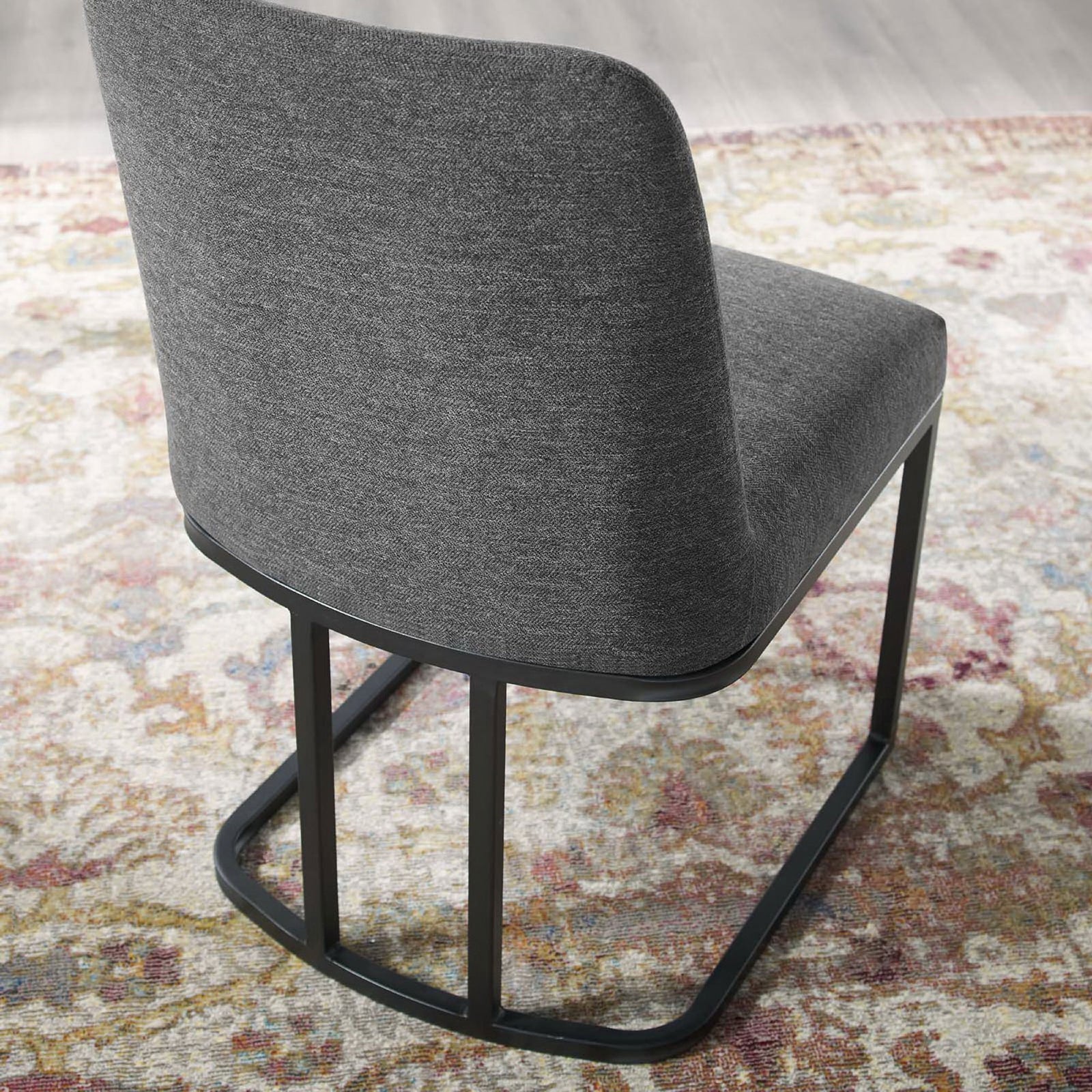 Charcoal dining chair on patterned rug showcasing curved backrest and open sled frame design || EEI-3811-BLK-CHA || back_angle_room