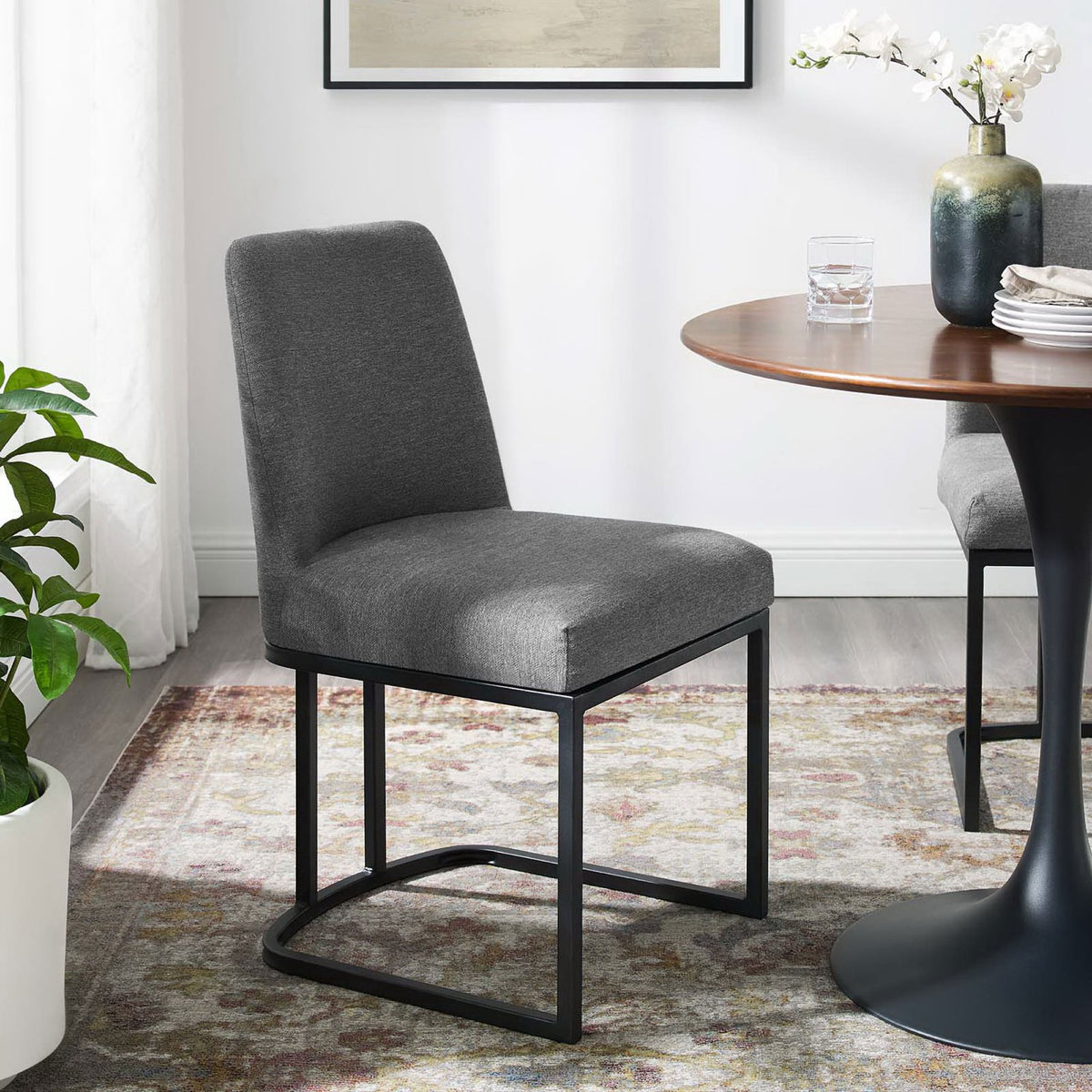 Charcoal upholstered dining chair paired with a round wood table in a bright contemporary dining room || EEI-3811-BLK-CHA || front_angle_room