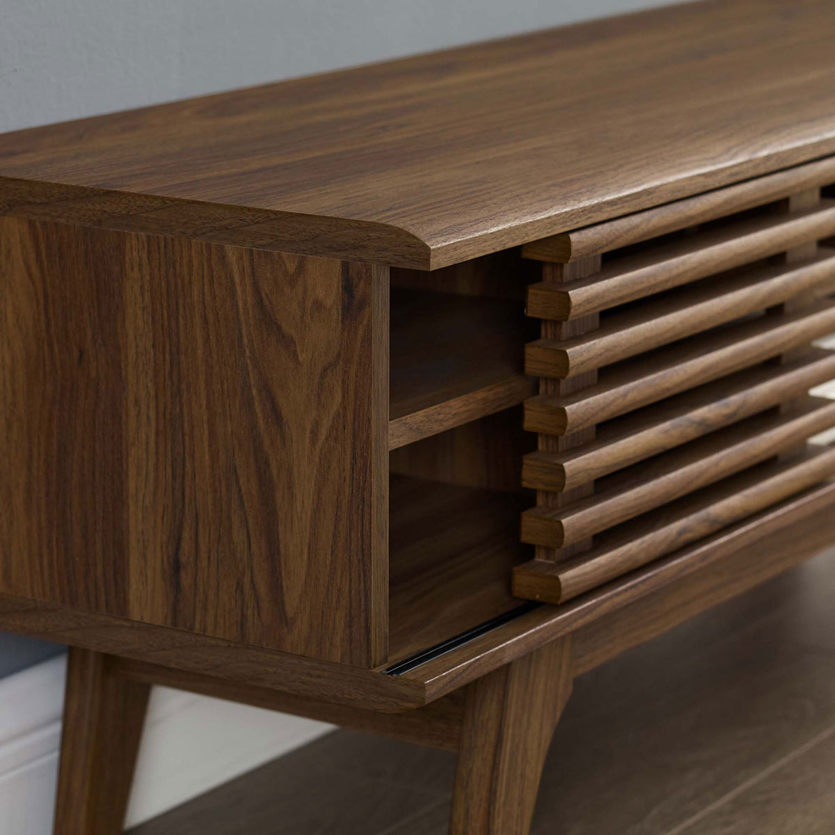 Corner detail of the TV console styled in a living room with wall and floor. || EEI-3837-WAL || detail_room