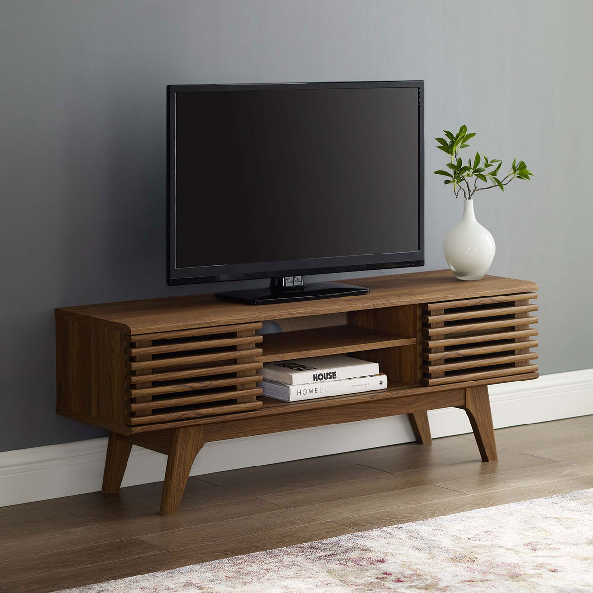 Walnut TV console supporting a flat-screen TV with decor in a modern living room. || EEI-3837-WAL || front_angle_room