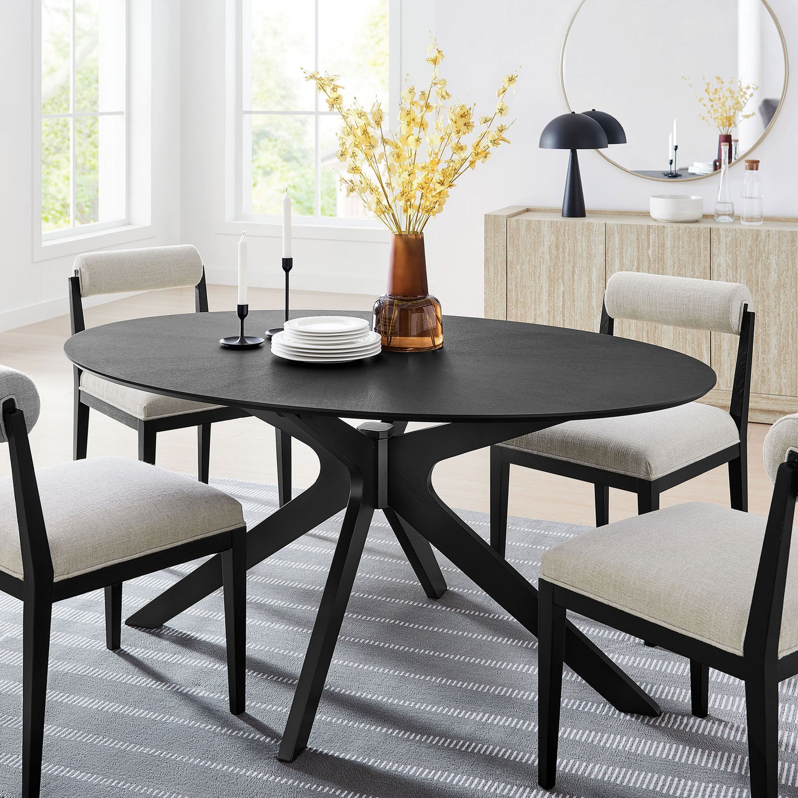 Black oval dining table styled in a bright dining room with coordinating chairs and modern decor || EEI-3848-BLK || front_angle_room