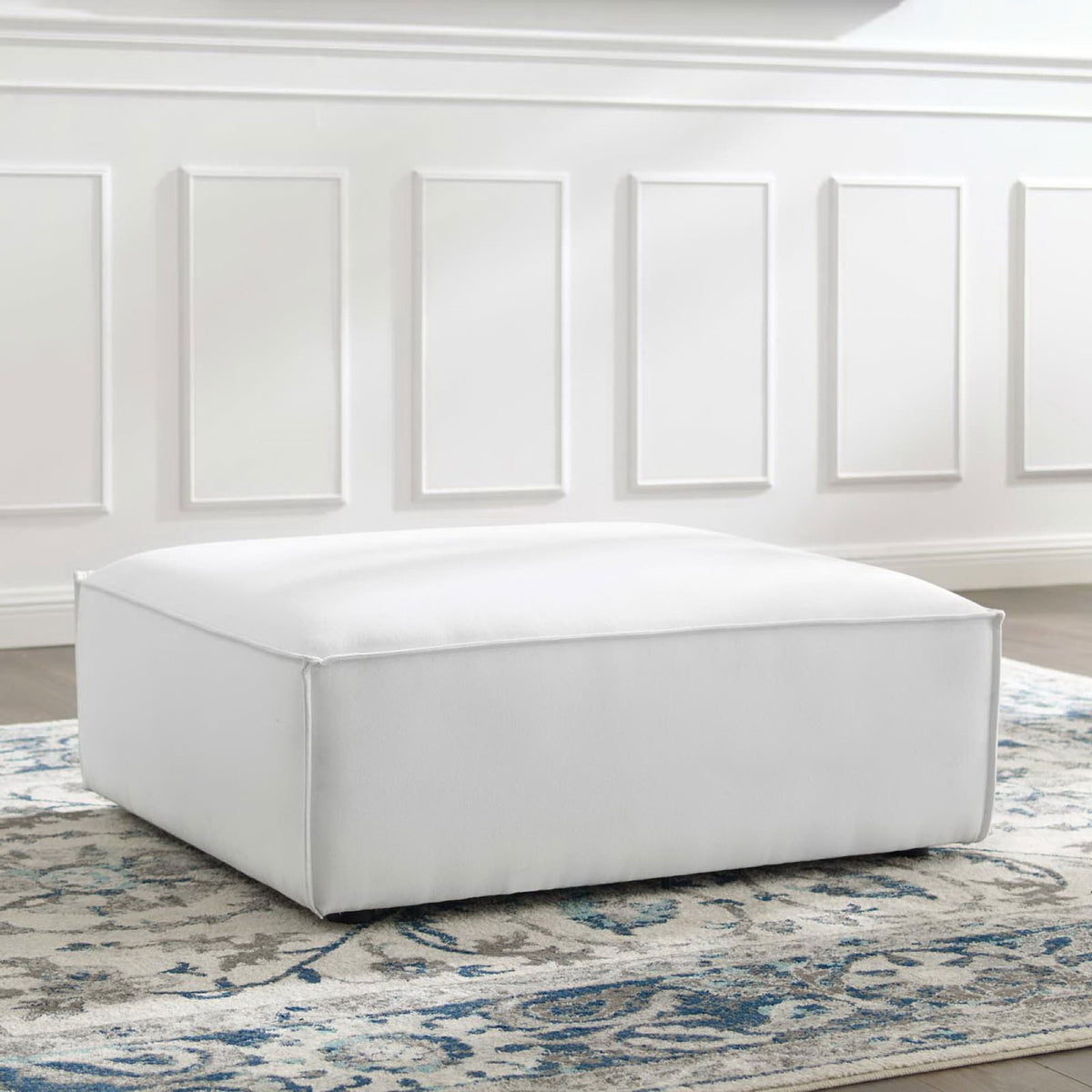 White Restore ottoman on a blue and gray patterned rug adding soft modern comfort to the living room || EEI-3873-WHI || front_angle_room