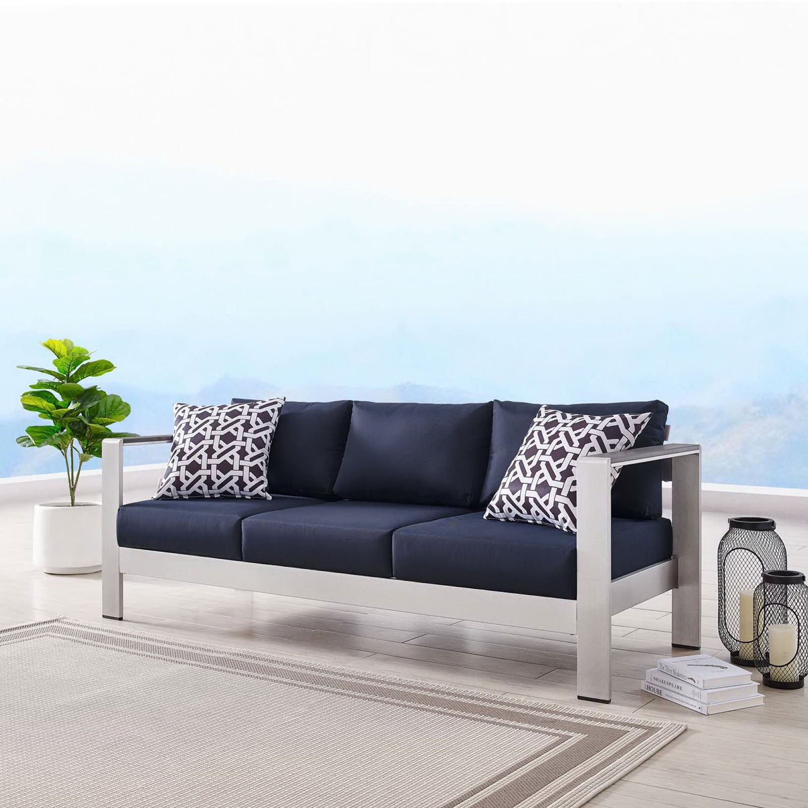 Shore sofa anchors a bright patio scene with rich navy cushions and a sleek silver frame || EEI-3917-SLV-NAV || front_angle_room