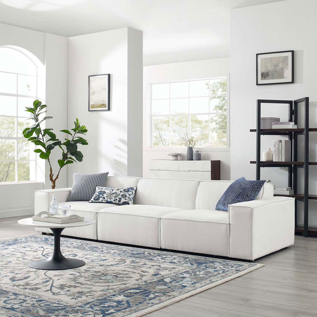 White Restore sectional sofa arranged in a bright living room with rug, coffee table, and decor accents. || EEI-4112-WHI || front_angle_room