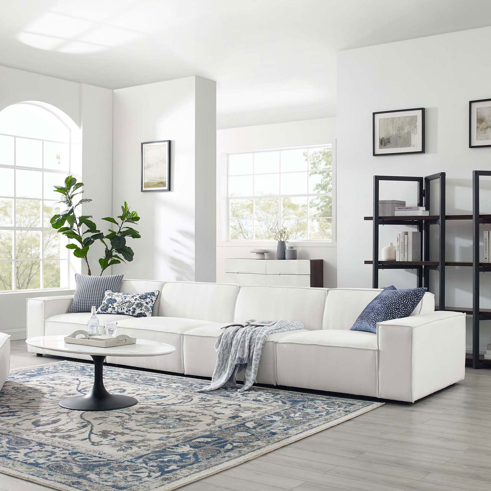 White modular sectional sofa styled in a bright living room with accent pillows and area rug. || EEI-4114-WHI || front_angle_room