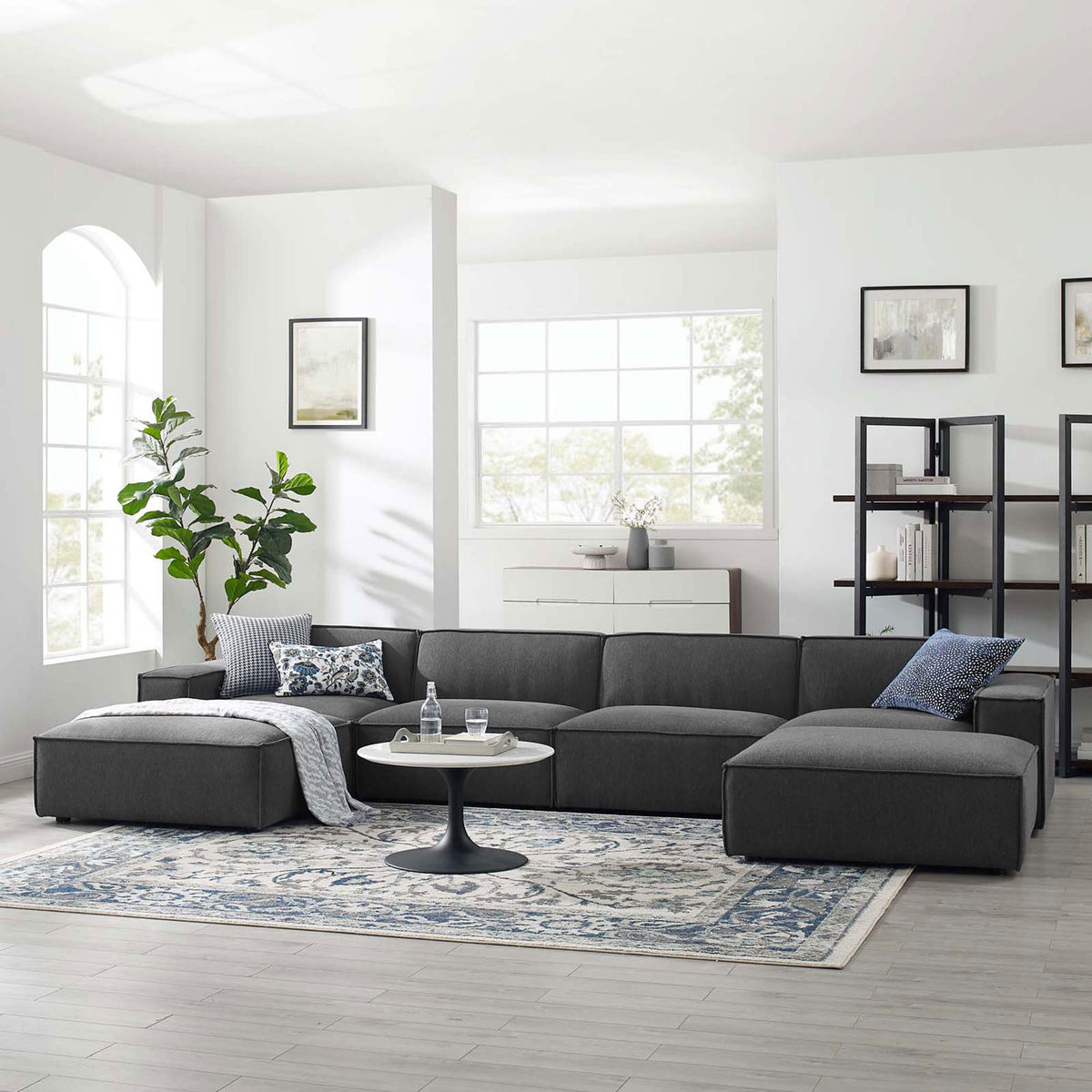 Charcoal gray Restore sectional arranged in a bright living room with rug, coffee table, and decor accents. || EEI-4116-CHA || front_angle_room