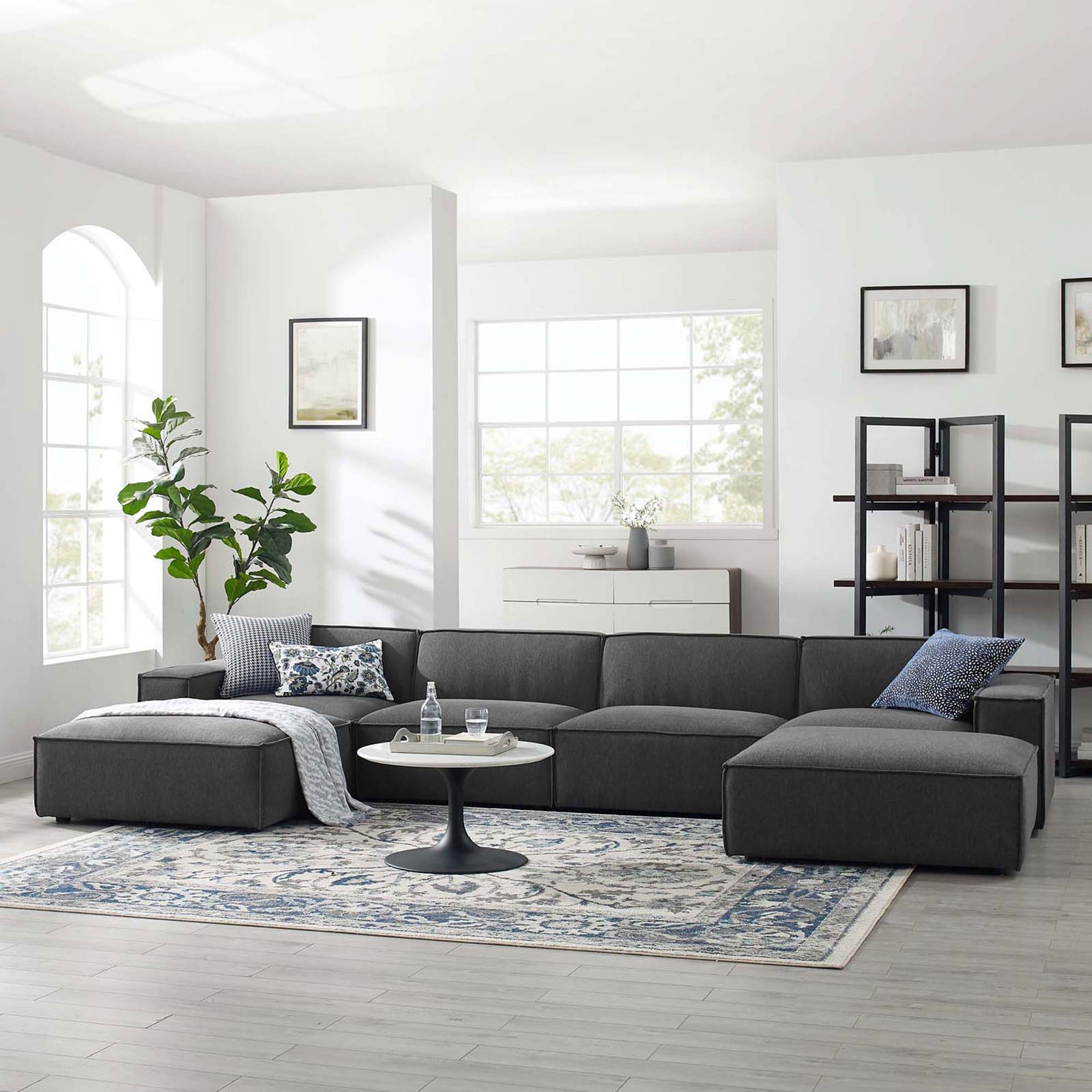 Charcoal gray Restore sectional arranged in a bright living room with rug, coffee table, and decor accents. || EEI-4116-CHA || front_angle_room