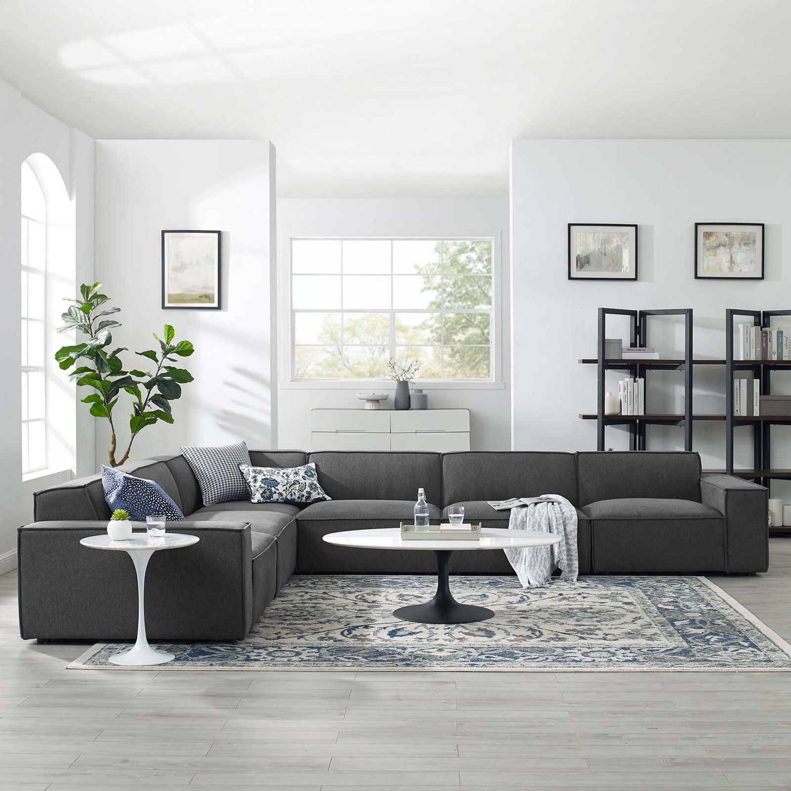 Charcoal modular sectional styled in a spacious living room with accent pillows, rug, and modern tables || EEI-4119-CHA || front_angle_room