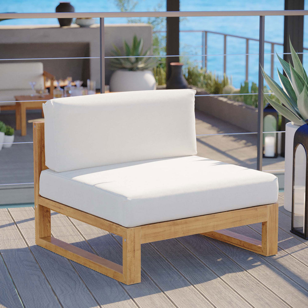 Teak armless chair brings airy, modern comfort to an oceanfront terrace with plush white outdoor cushions || EEI-4125-NAT-WHI || front_angle_room