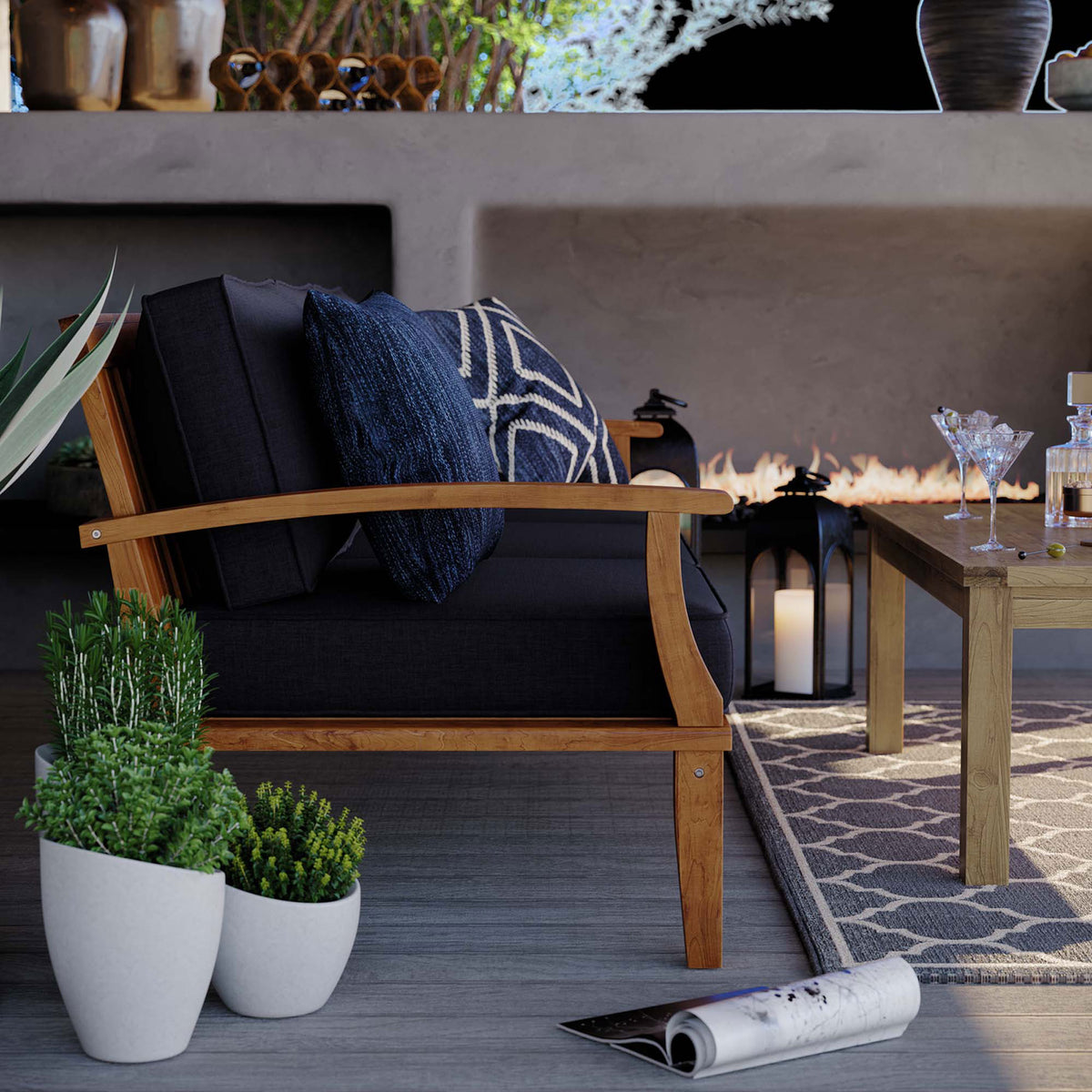 Side of teak outdoor sofa layered with patterned navy pillows beside modern planters and table || EEI-4176-NAT-NAV || detail_room