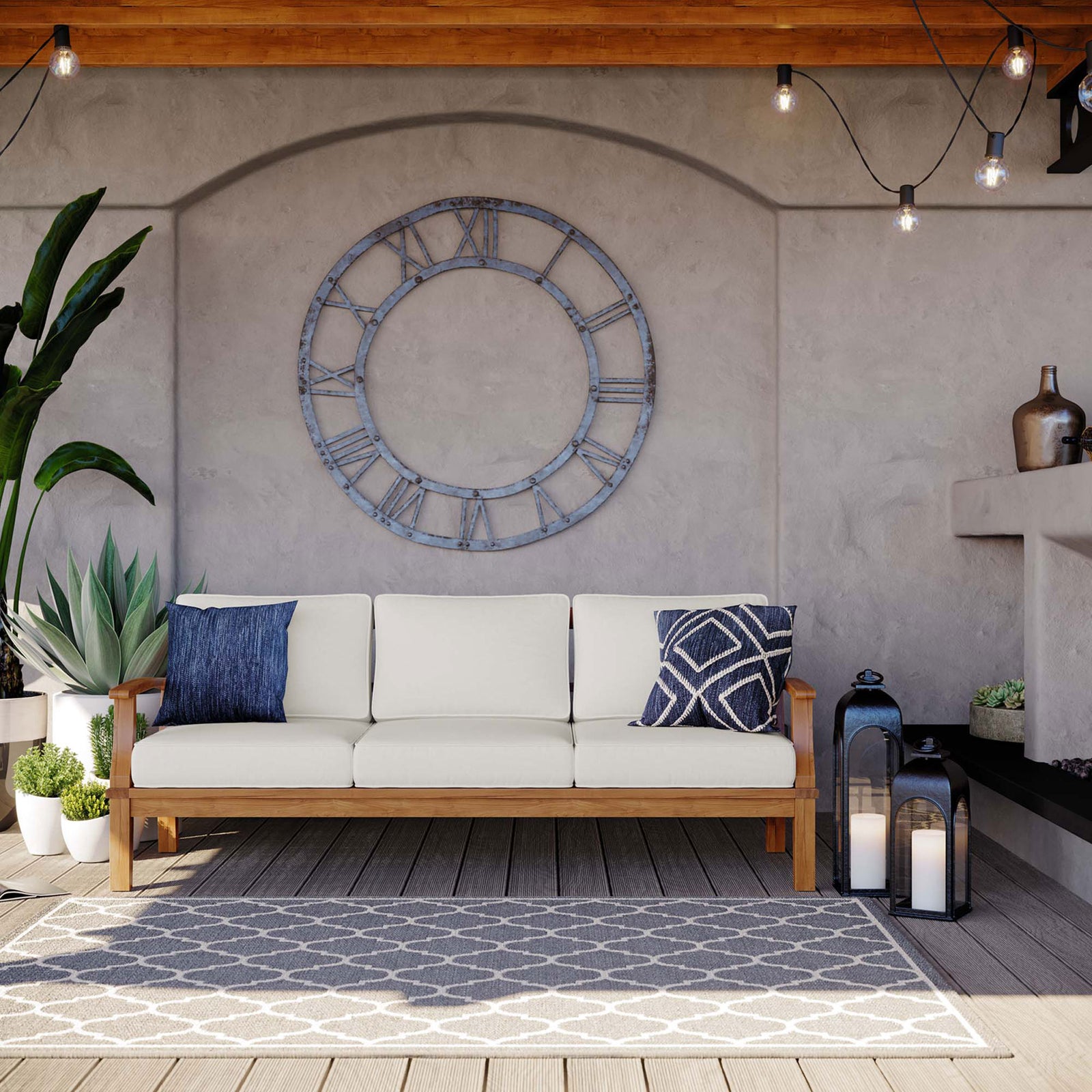 White cushioned teak sofa arranged on a covered deck with lanterns, patterned rug, and wall clock || EEI-4176-NAT-WHI || front_angle_room
