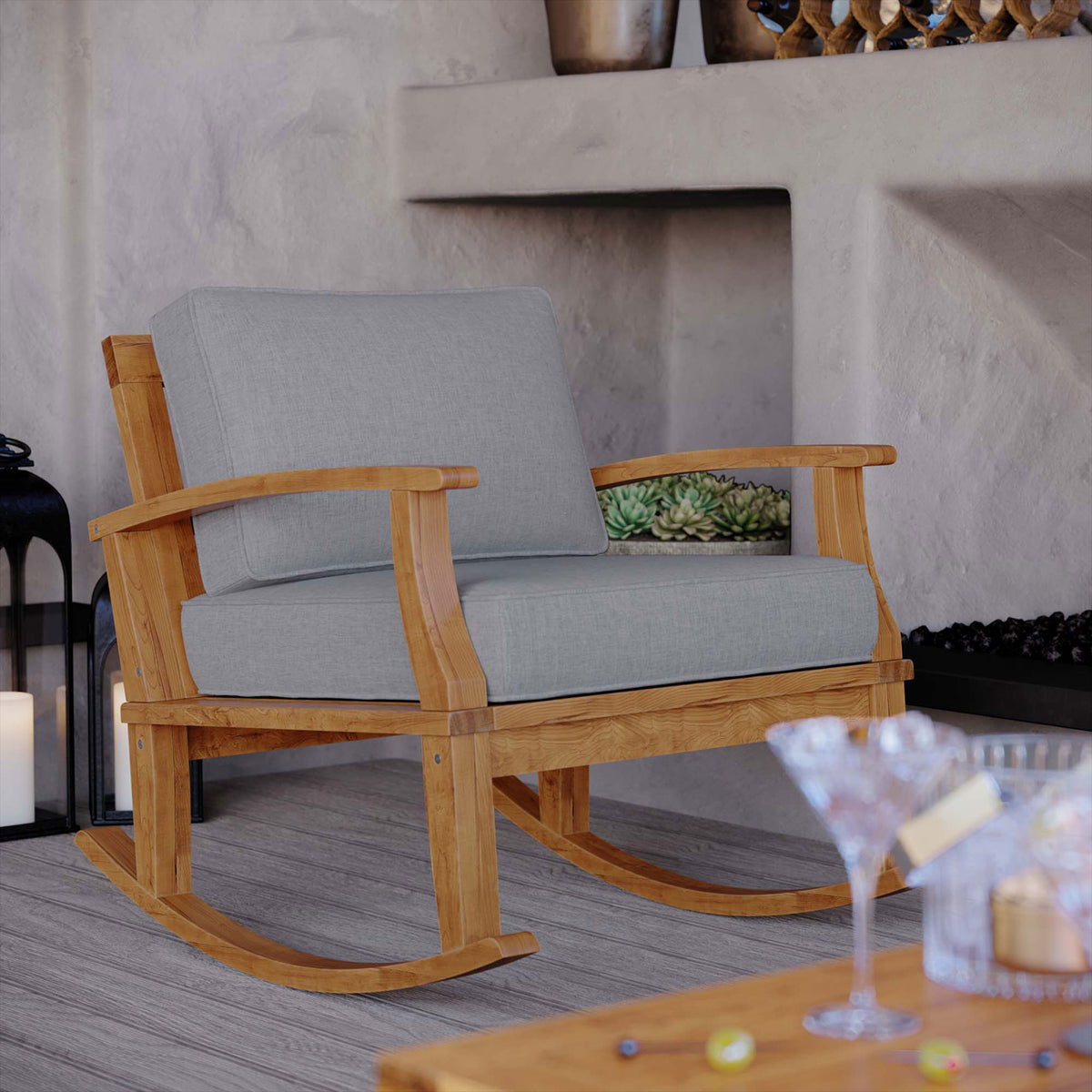 Marina teak rocking chair with gray cushions styled on a covered patio for cozy outdoor lounging || EEI-4177-NAT-GRY || front_angle_room