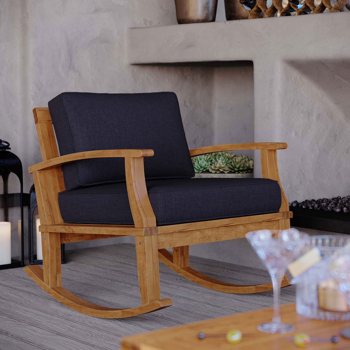 Marina teak rocking chair with navy cushions styled on a covered patio for cozy outdoor seating || EEI-4177-NAT-NAV || front_angle_room