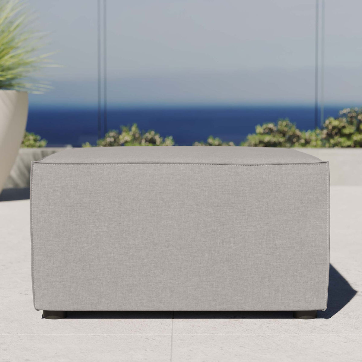 Gray outdoor sectional ottoman styled on a sunny patio with coastal backdrop and lush greenery || EEI-4211-GRY || front_room