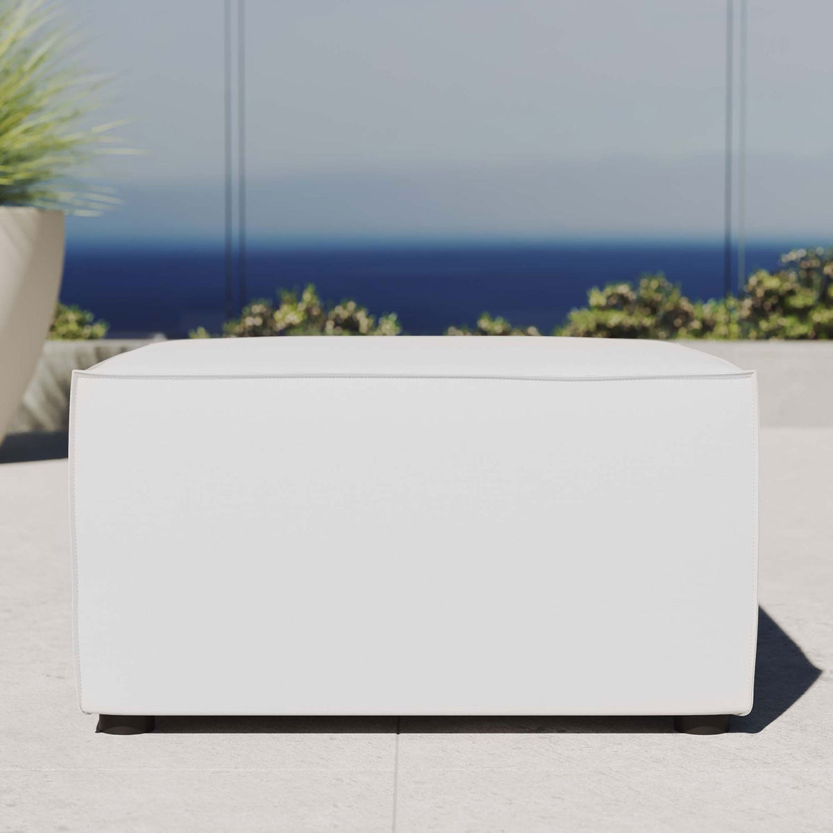 White outdoor sectional ottoman styled on a bright patio with ocean view and greenery || EEI-4211-WHI || front_room