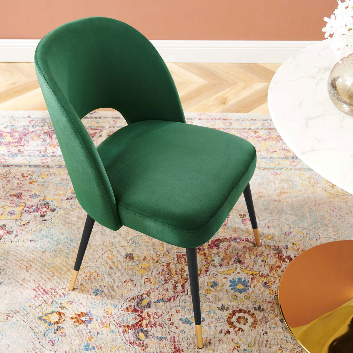 Emerald velvet dining chair styled with a modern table and colorful rug in a warm dining space. || EEI-4212-EME || top_room