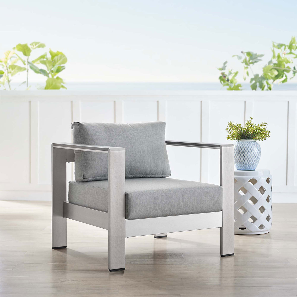 Sunbrella(r) armchair styled with coastal decor creates a bright, welcoming outdoor lounge spot || EEI-4225-SLV-GRY || front_angle_room