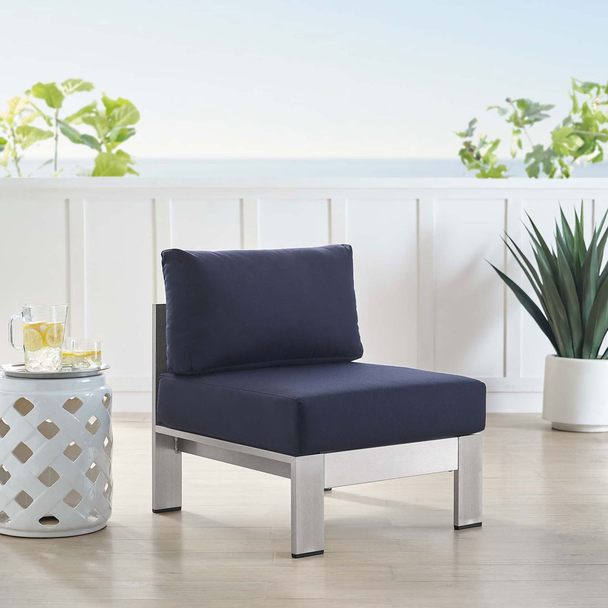 Navy armless Sunbrella(r) chair completes an inviting coastal-style outdoor sitting area || EEI-4227-SLV-NAV || front_angle_room