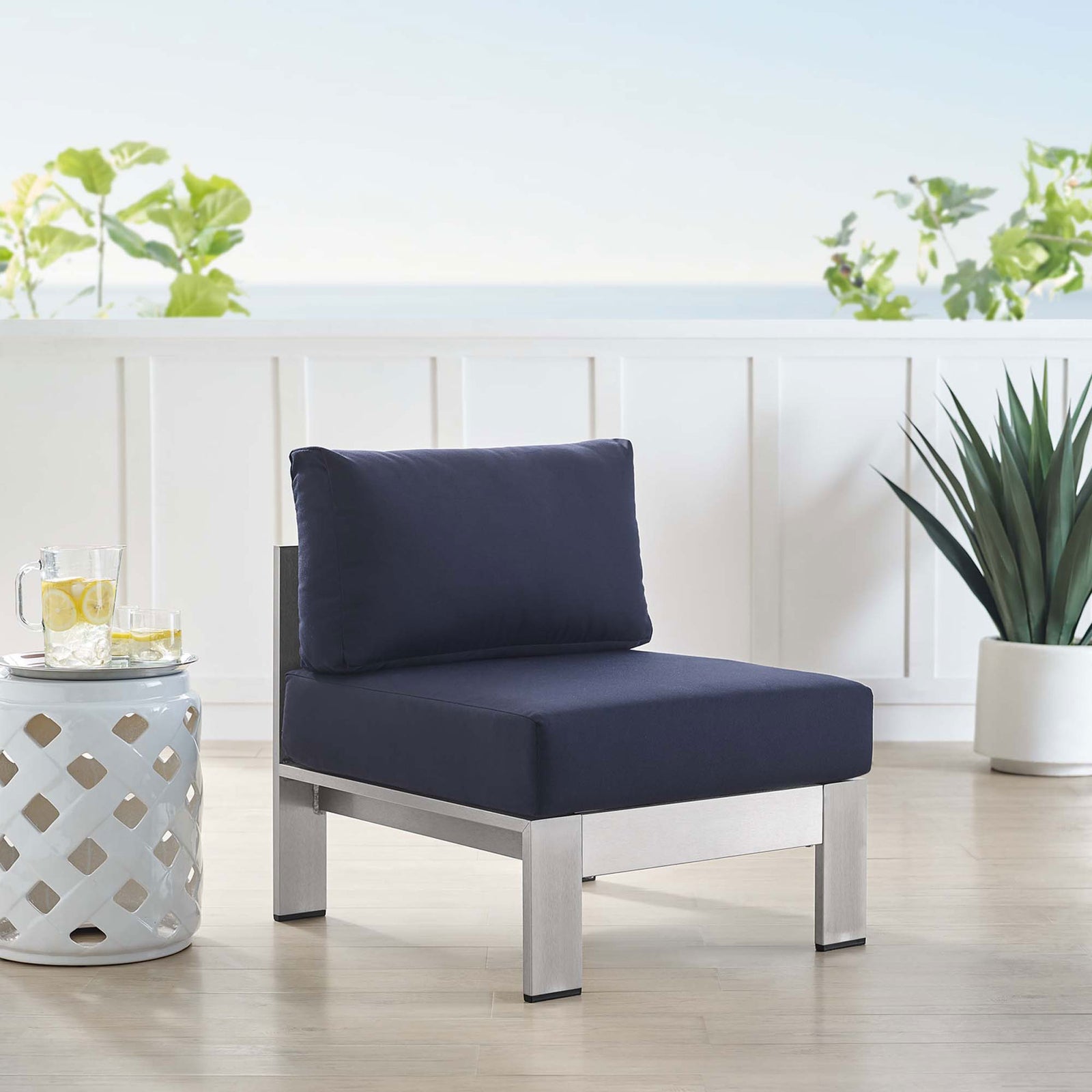 Navy armless Sunbrella(r) chair completes an inviting coastal-style outdoor sitting area || EEI-4227-SLV-NAV || front_angle_room