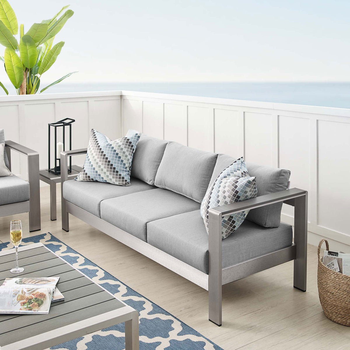 Shore sofa anchors a breezy patio with soft gray cushions and coordinating accent pillows || EEI-4228-SLV-GRY || front_angle_room
