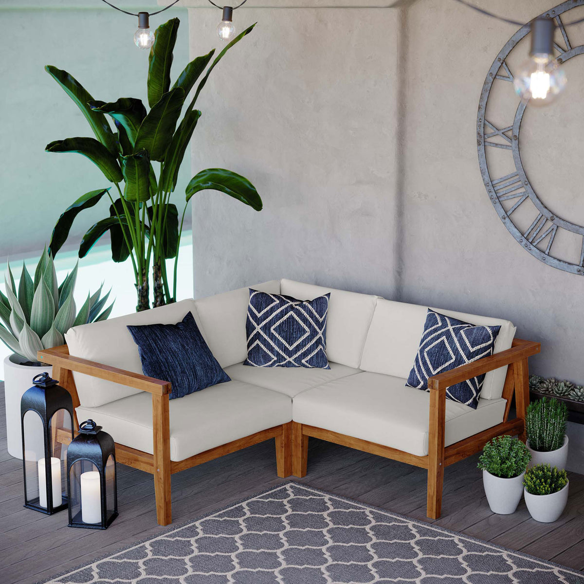 Complete teak sectional seating area with white cushions, blue accents, plants, and outdoor rug || EEI-4258-NAT-WHI-SET || front_angle_room
