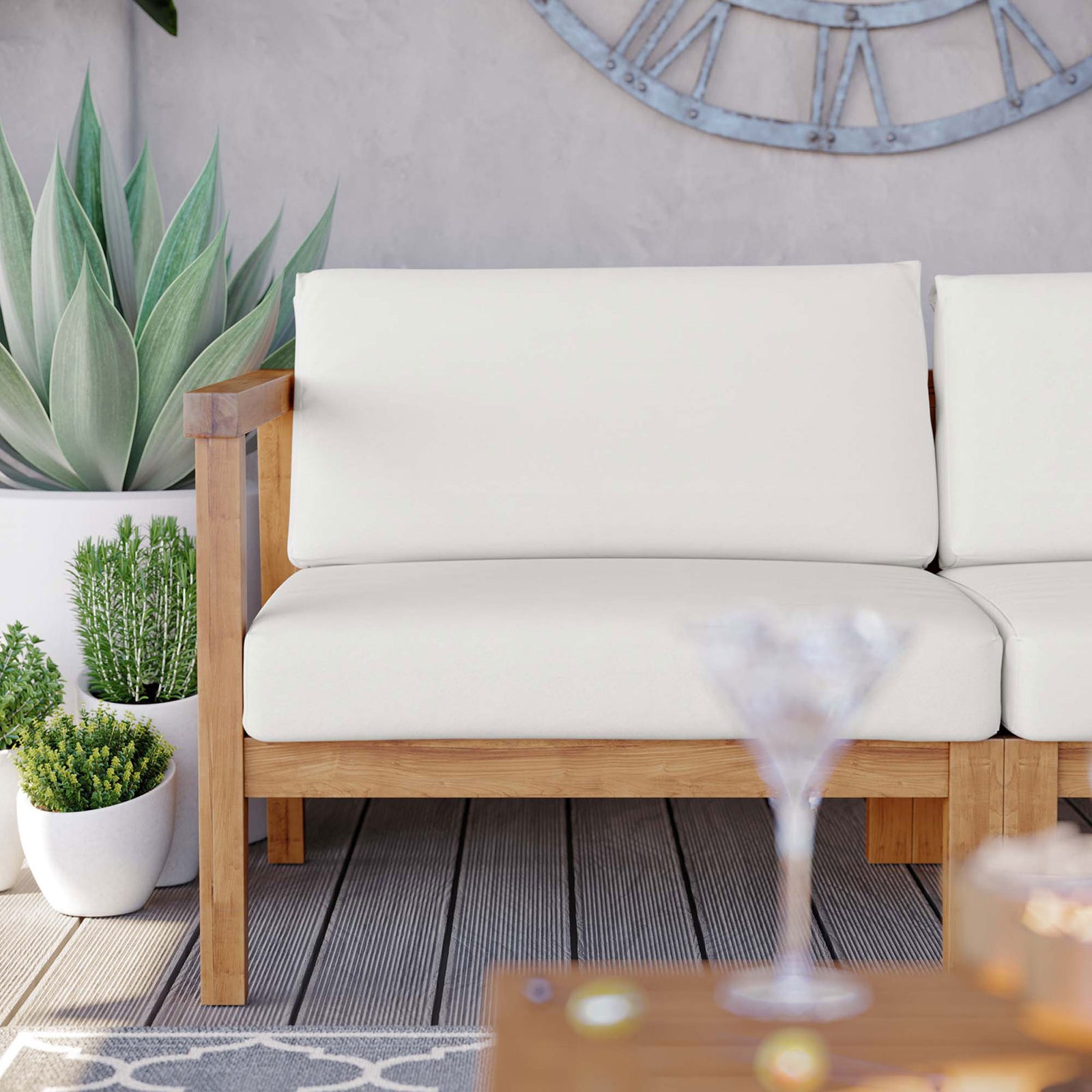 Bayport teak loveseat with clean-lined arms and smooth white cushions framed by modern planters || EEI-4259-NAT-WHI-SET || front_angle_partial_room