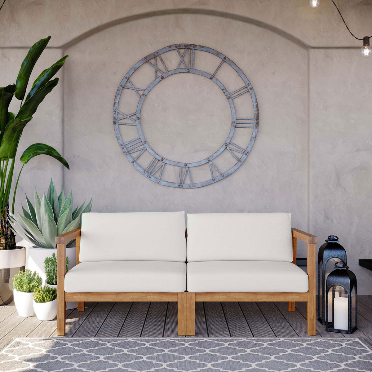 Bayport outdoor teak loveseat with white cushions styled on a covered patio with plants and lanterns || EEI-4259-NAT-WHI-SET || front_room