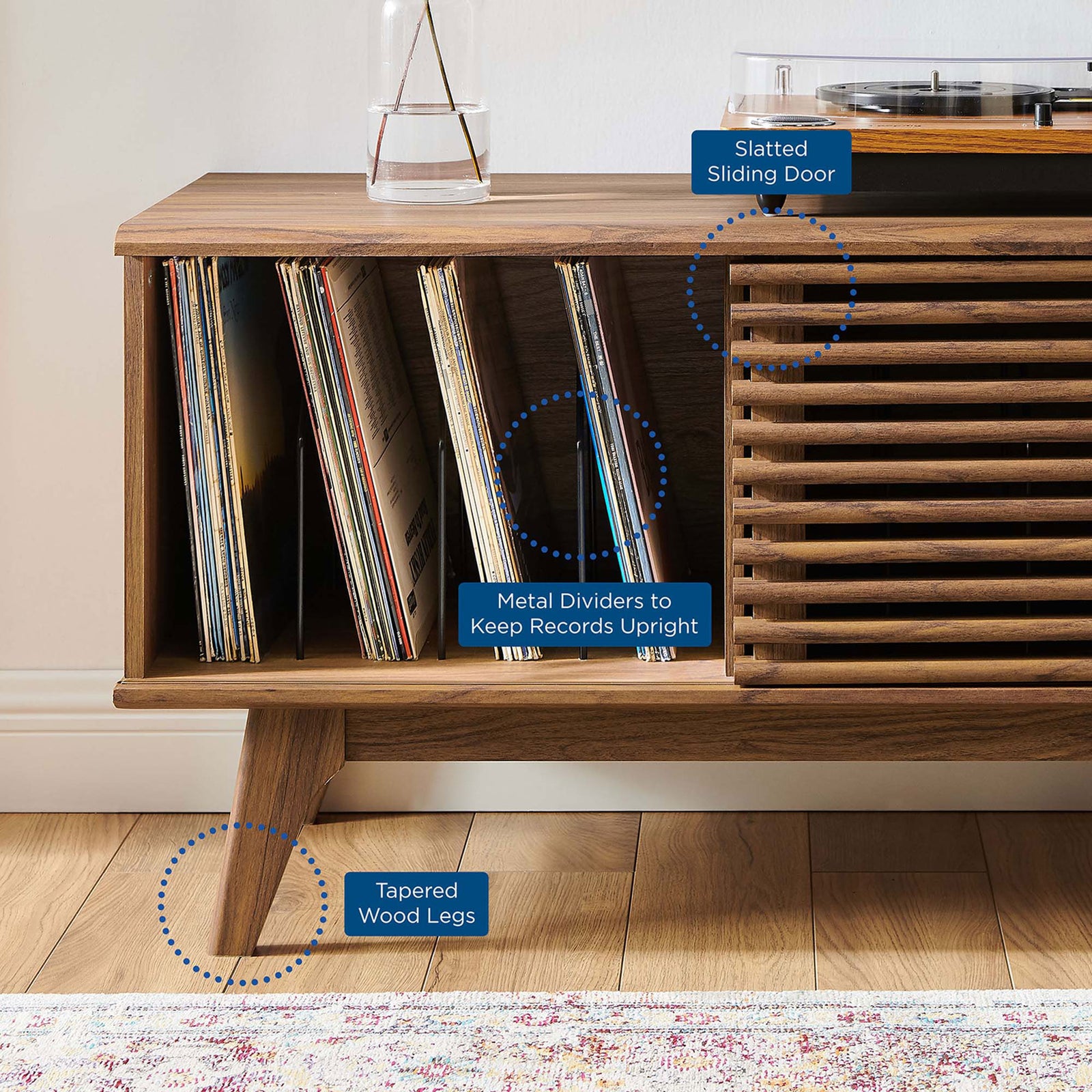Walnut record stand with slatted door, metal dividers, and tapered legs highlighted for vinyl storage. || EEI-4263-WAL || callout_room