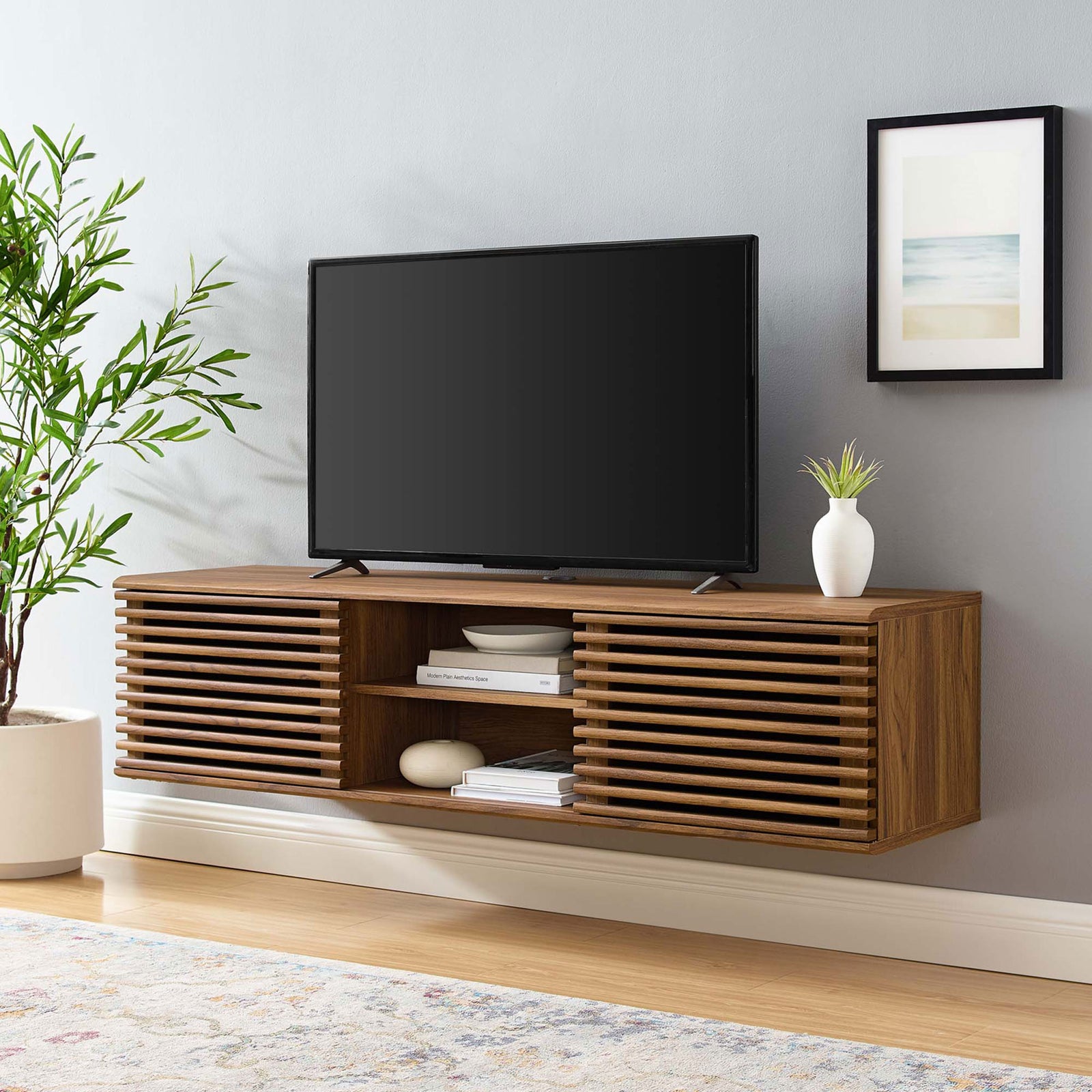 Spacious 60 inch wall-mounted media console styled under a large TV with books and decor accents. || EEI-4267-WAL || front_angle_room