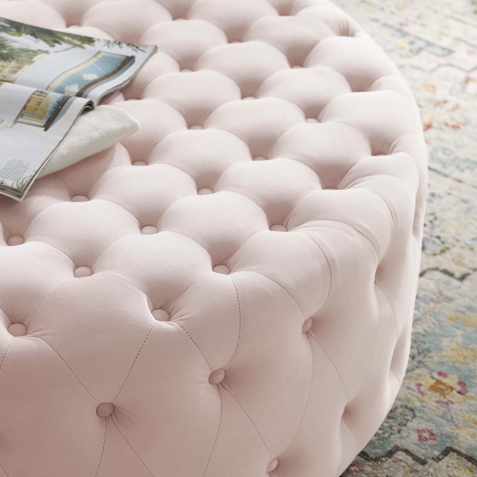 Tufted pink velvet ottoman styled with a magazine, adding soft texture to a patterned rug || EEI-4326-PNK || detail_room