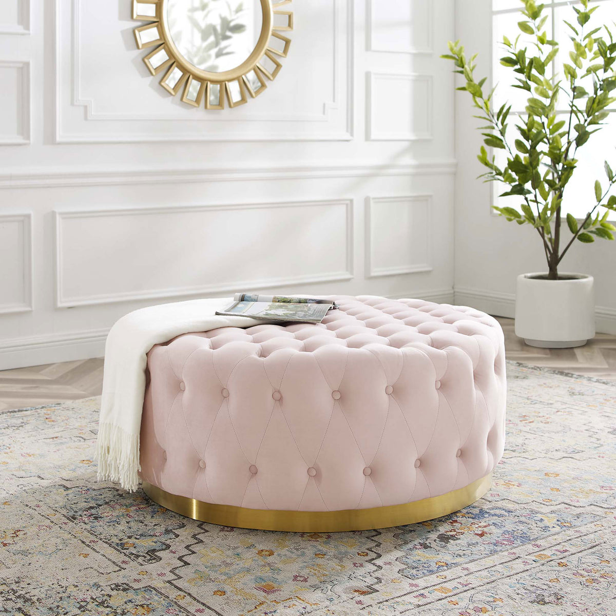 Pink tufted round ottoman with gold base styled in an elegant white living room || EEI-4326-PNK || front_angle_room