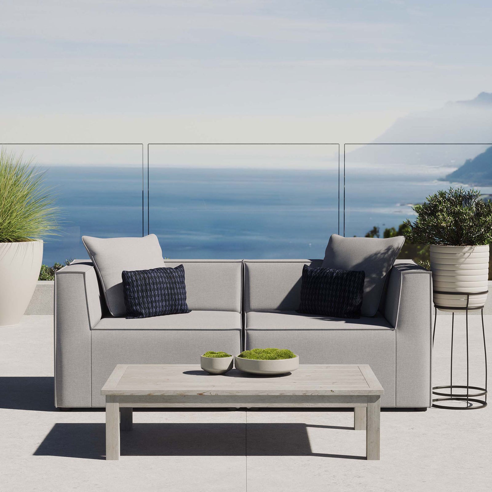 Gray upholstered patio loveseat creating a cozy seating spot overlooking a bright coastal view. || EEI-4377-GRY || front_room