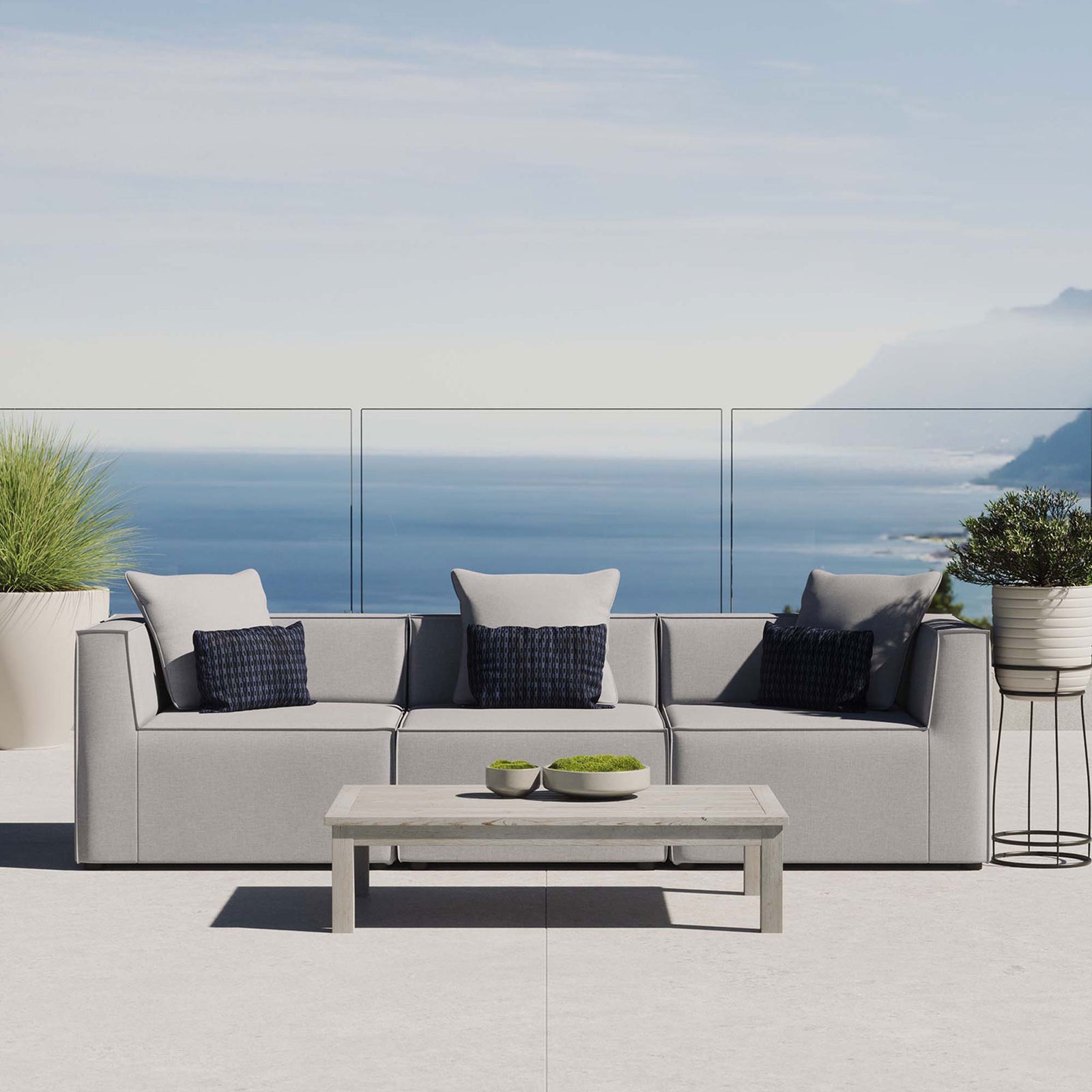 Gray outdoor sectional sofa with accent pillows styled on a modern patio overlooking the ocean. || EEI-4379-GRY || front_room
