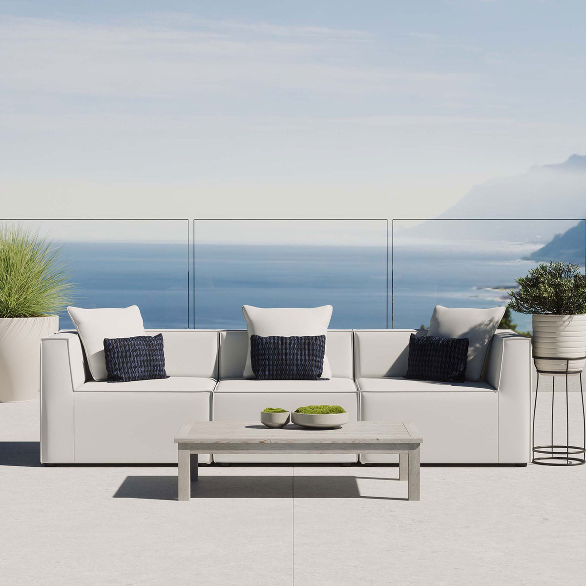 White outdoor sectional sofa with accent pillows styled on a sunlit patio by the ocean. || EEI-4379-WHI || front_room