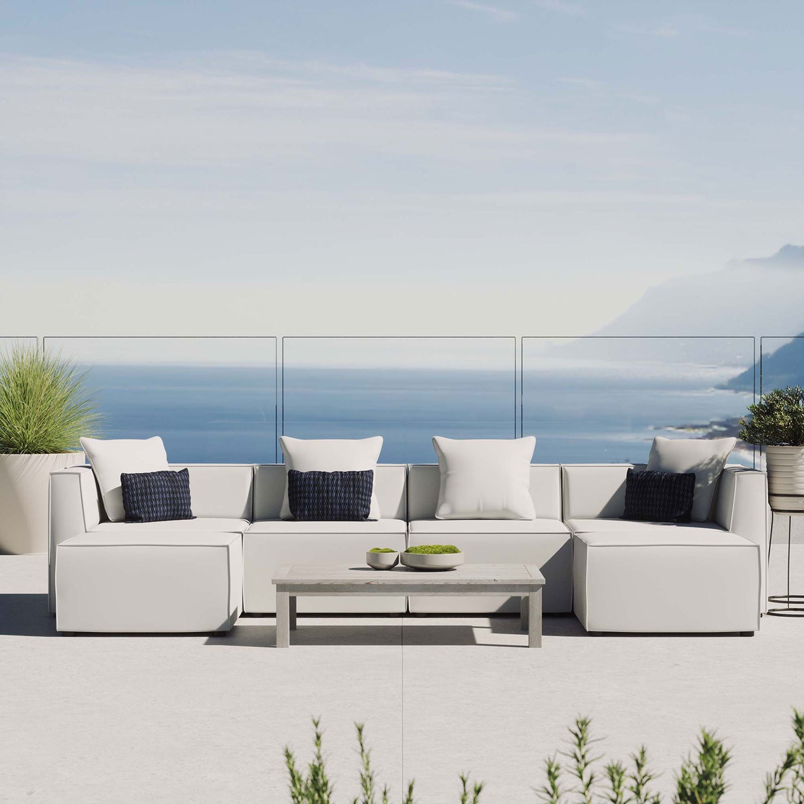 White Saybrook outdoor sectional styled on a coastal patio with accent pillows and a modern coffee table. || EEI-4383-WHI || front_room