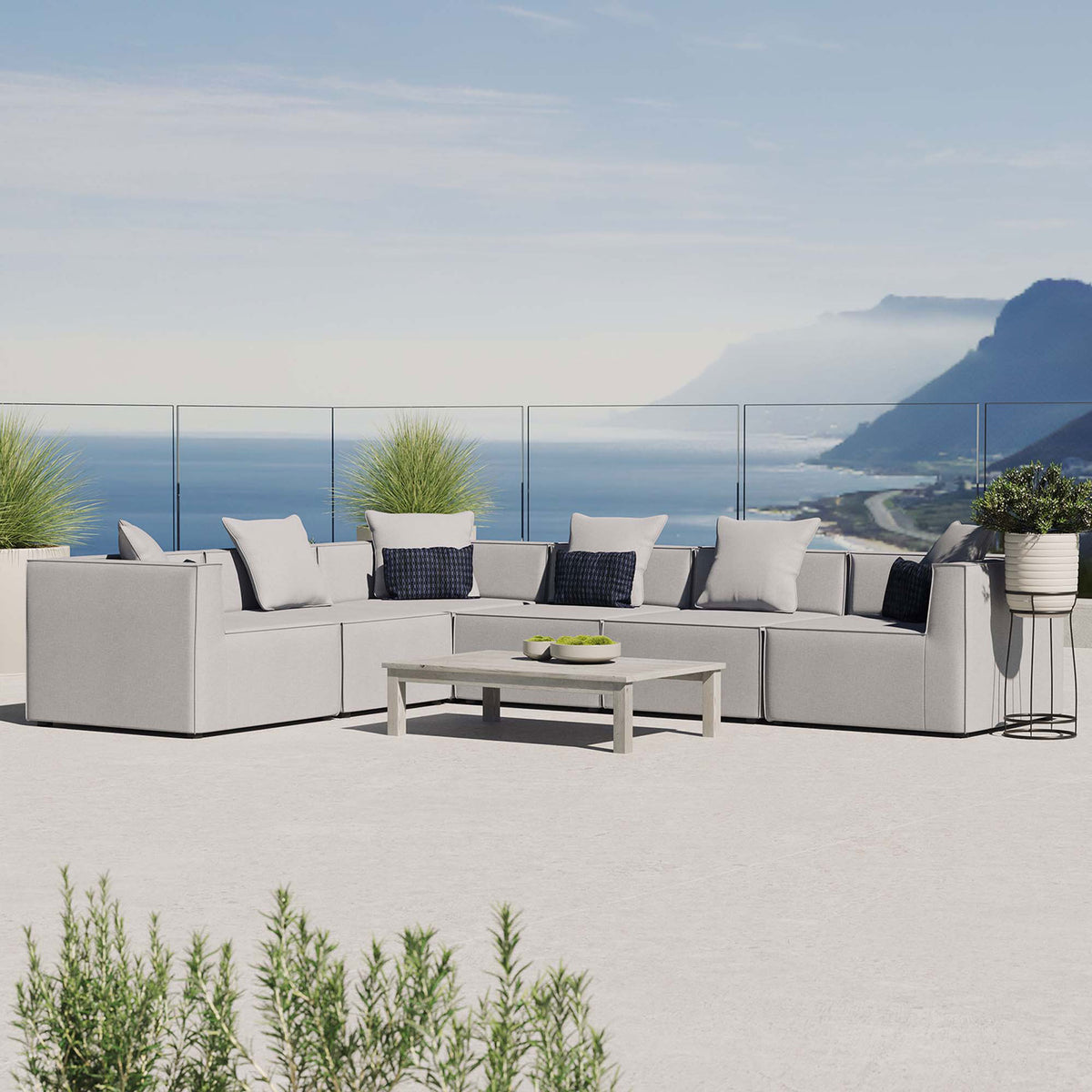 Gray outdoor sectional sofa styled on a balcony with coastal view and lush greenery || EEI-4385-GRY || front_angle_room