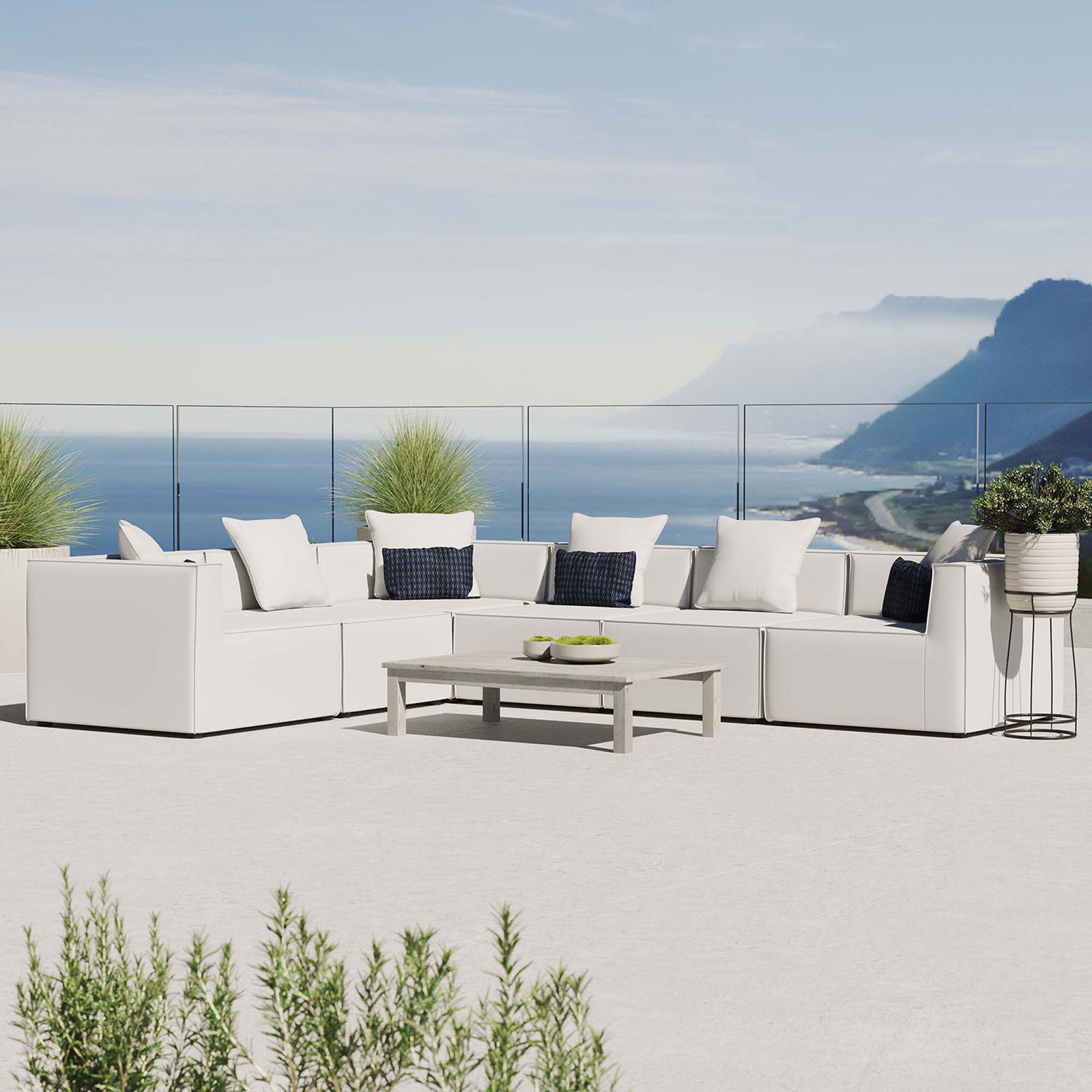 White outdoor sectional sofa styled on a balcony with ocean backdrop and lush greenery || EEI-4385-WHI || front_angle_room