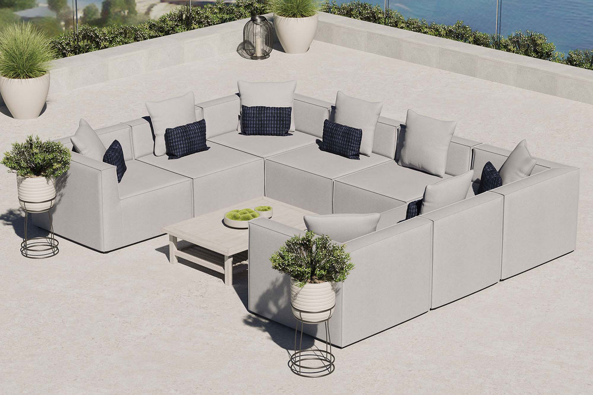 Gray Saybrook 8-piece outdoor sectional arranged on a sunny terrace with coordinating accent tables. || EEI-4388-GRY || front_angle_room