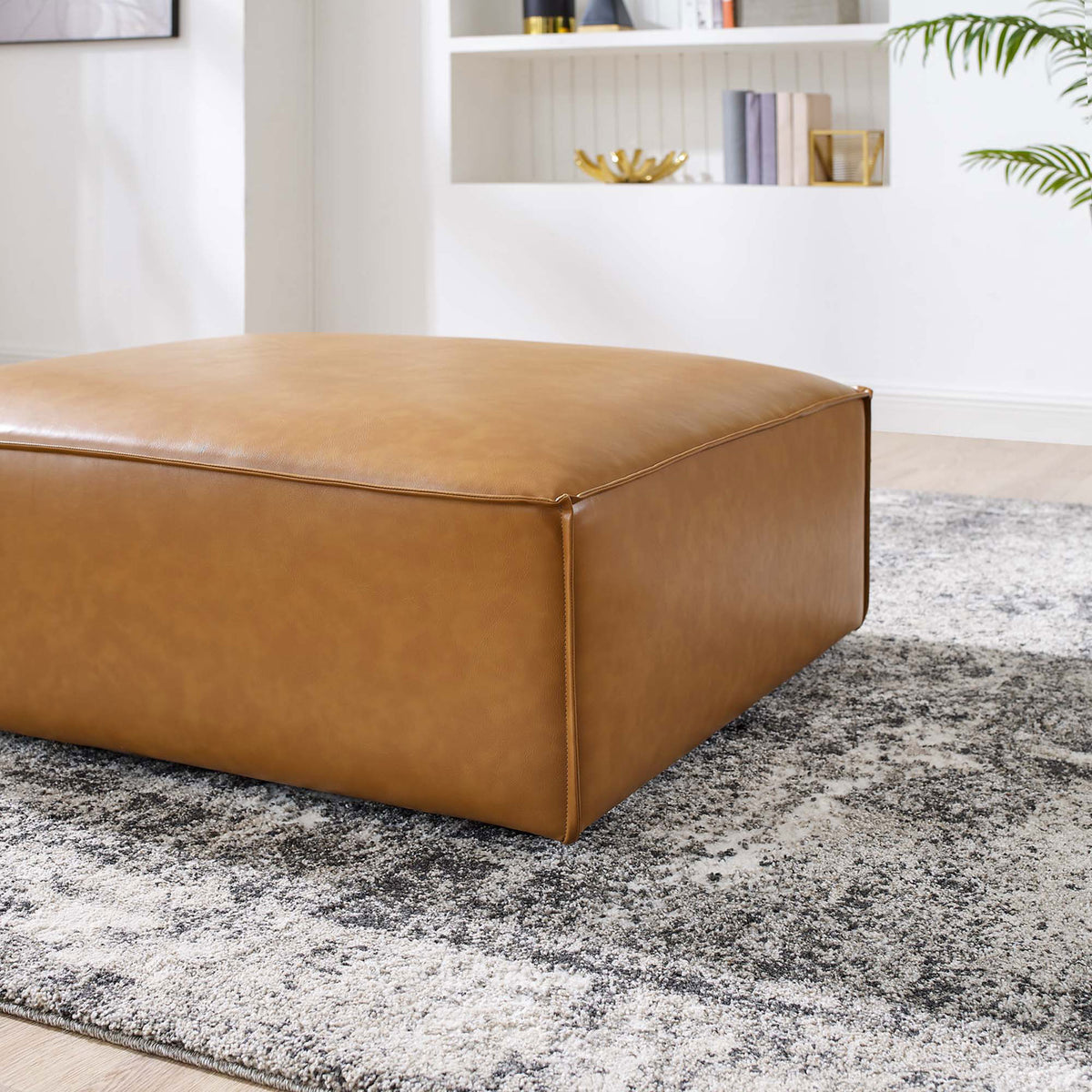 Tan vegan leather ottoman styled on a modern area rug, adding warmth and texture to the living room || EEI-4496-TAN || front_angle_room