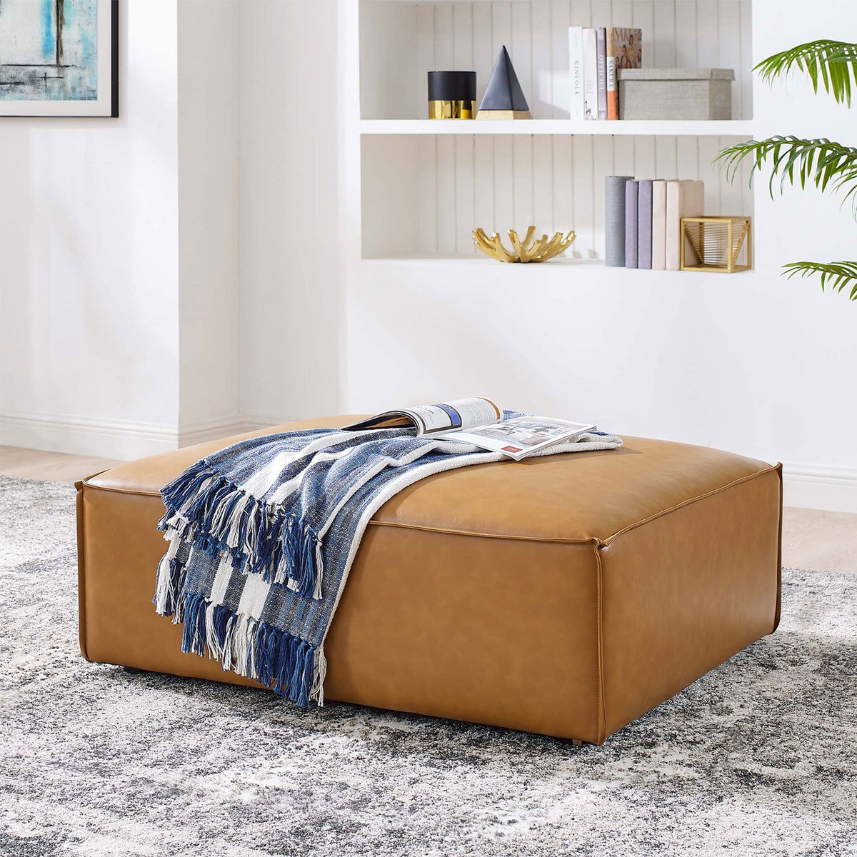 Tan vegan leather ottoman with throw blanket creating a cozy centerpiece for the lounge seating area || EEI-4496-TAN || front_room