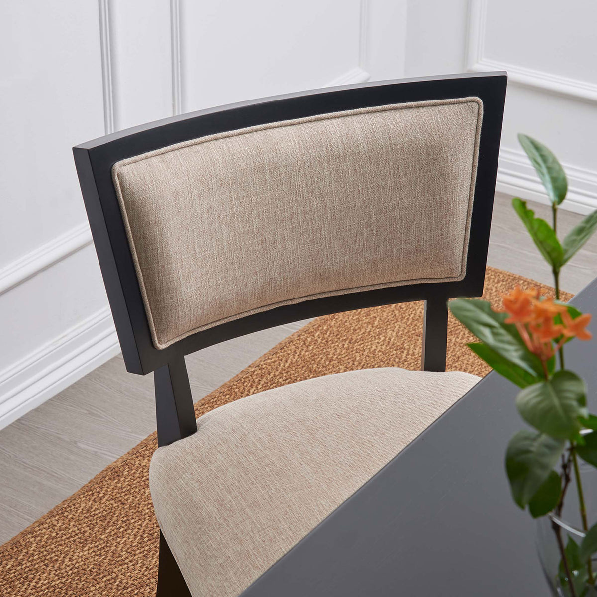 Dining chair in a dining room showcasing the textured beige fabric and gently curved black backrest || EEI-4557-BEI || detail_room