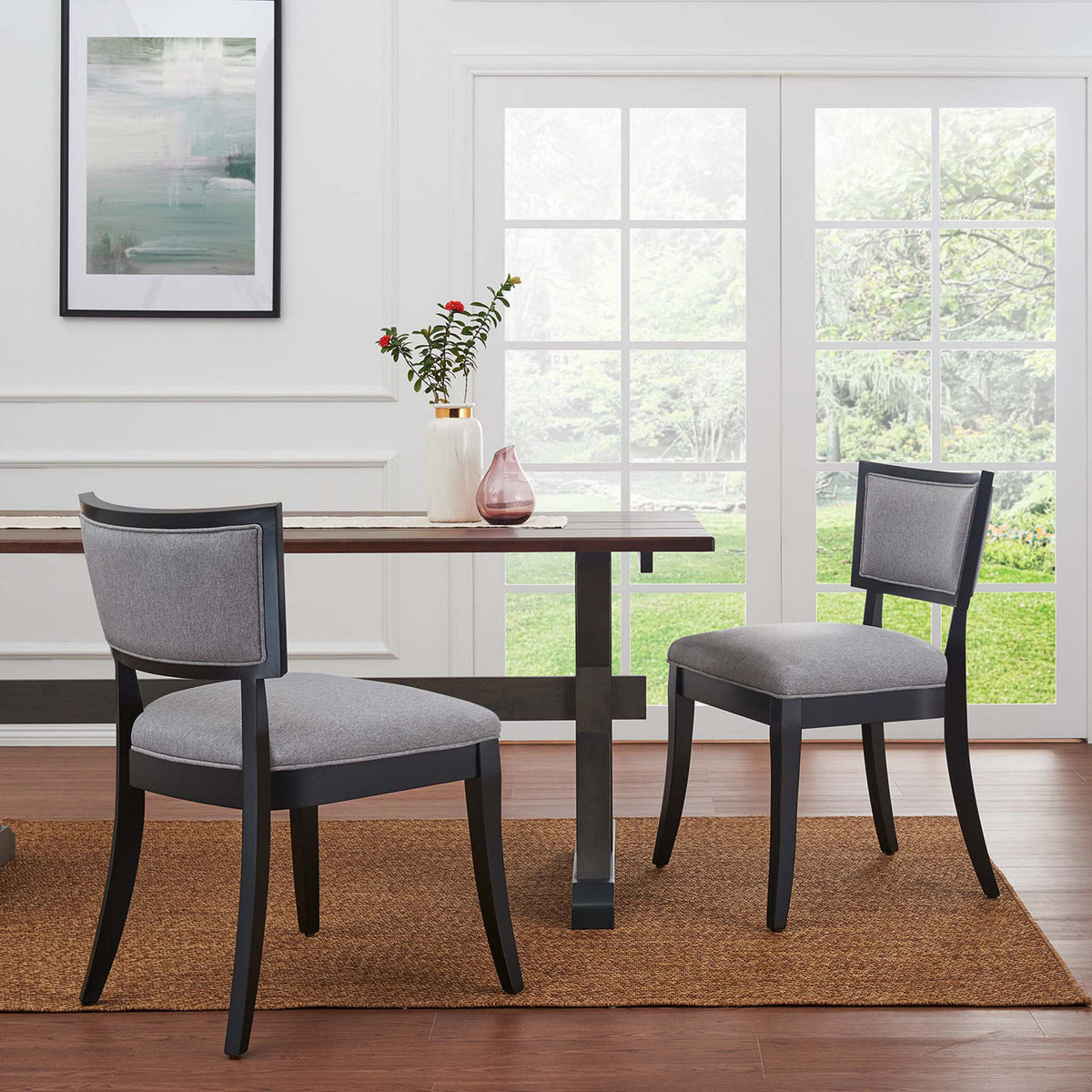 Pair of light gray dining chairs around a modern table in a bright dining room || EEI-4557-LGR || side_multi_room