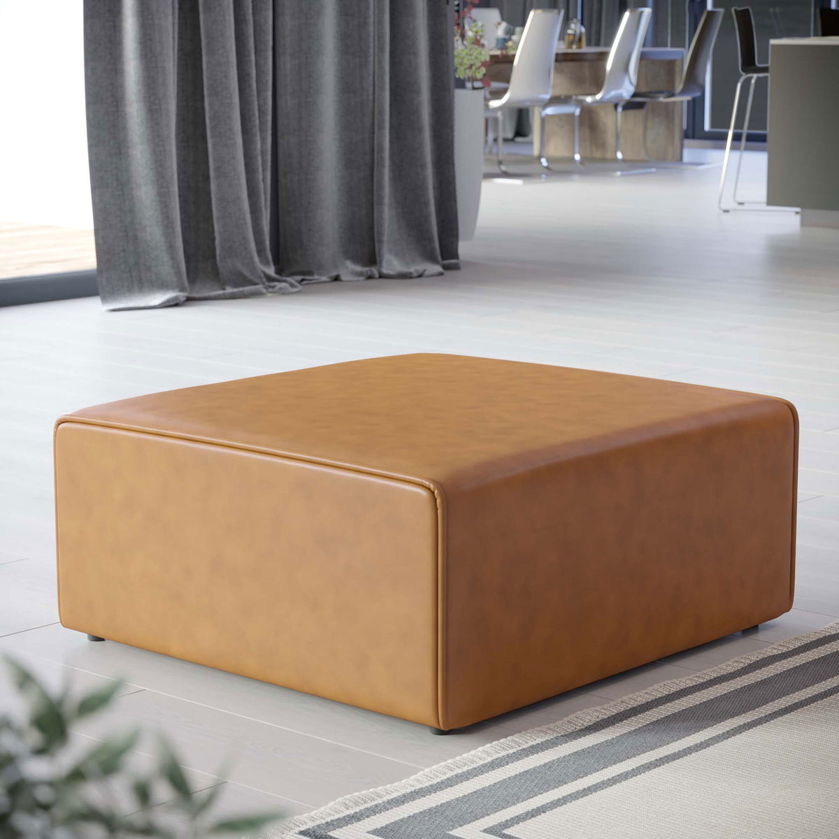Mingle tan vegan leather ottoman centered in a contemporary living room with sleek floors and draped curtains || EEI-4624-TAN || front_angle_room