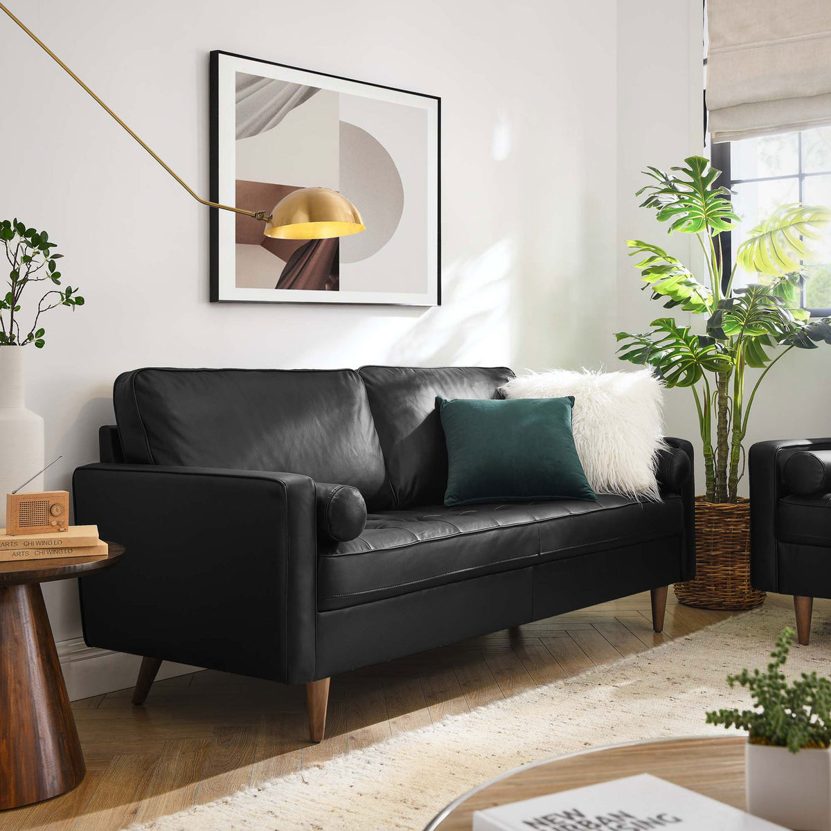 Black leather Valour apartment sofa styled in a bright living room with cozy pillows, rug, and warm wood accents. || EEI-4633-BLK || front_angle_room