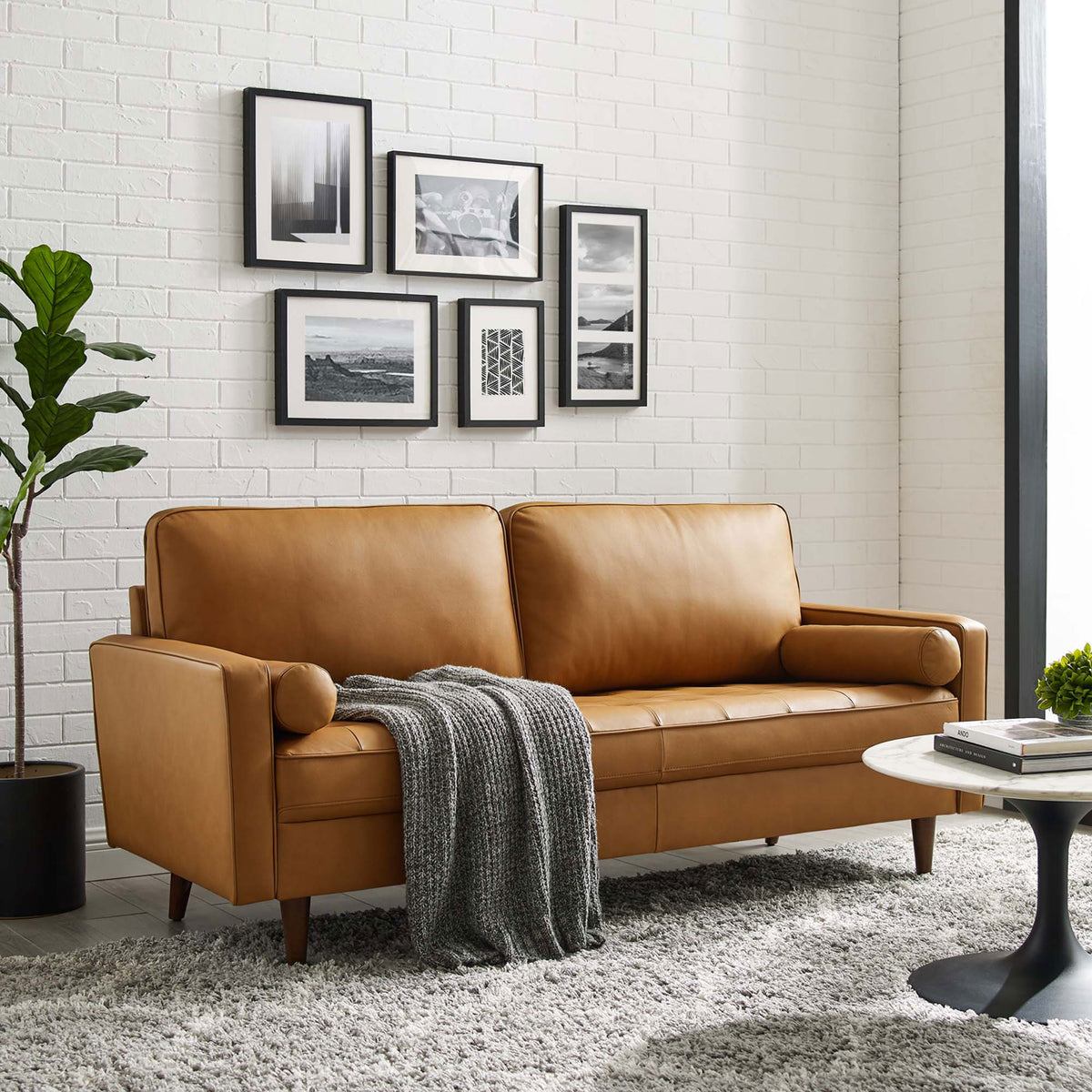Tan leather sofa styled in a bright living room with rug, throw blanket, and wall art || EEI-4633-TAN || front_angle_room