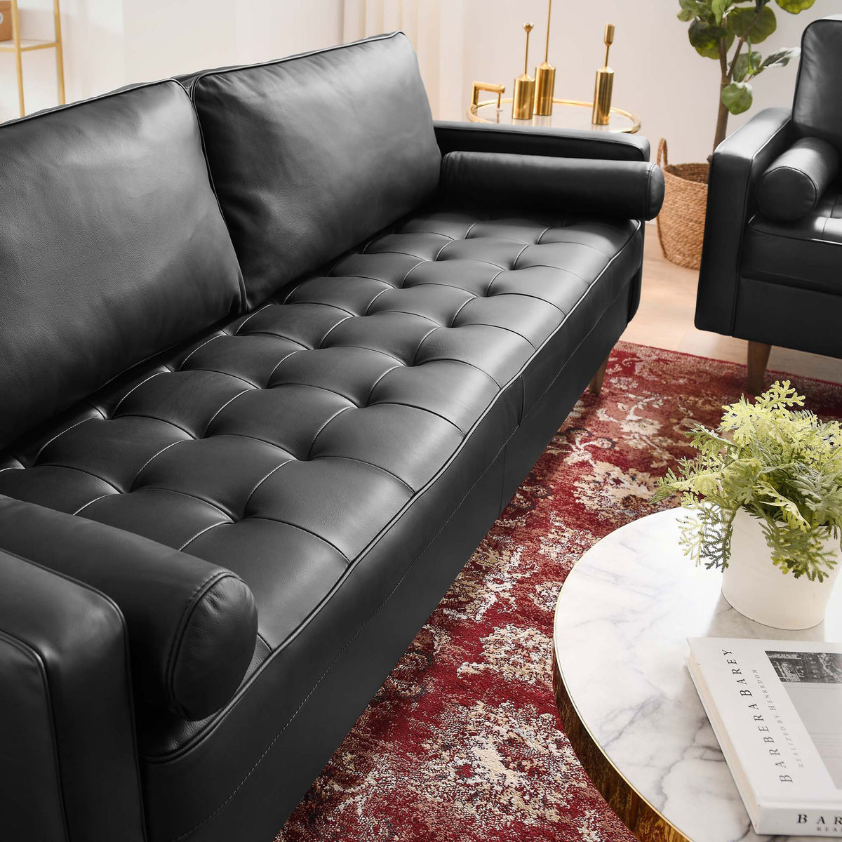 Button tufted black leather seat on the Valour sofa pairs with a rich red rug and brass accents for a luxe lounge look. || EEI-4634-BLK || detail_room