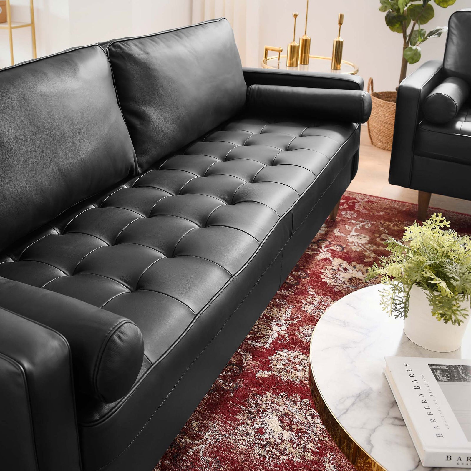 Button tufted black leather seat on the Valour sofa pairs with a rich red rug and brass accents for a luxe lounge look. || EEI-4634-BLK || detail_room