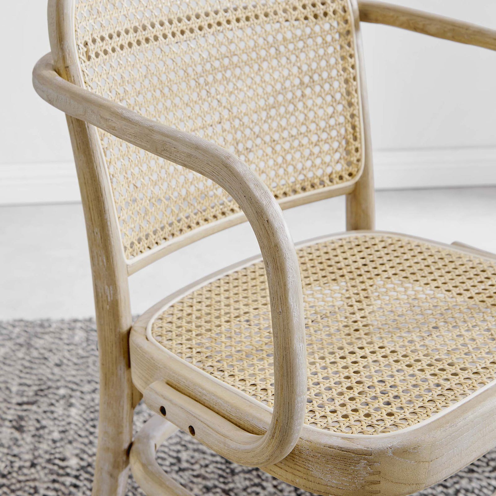 Winona dining chair styled on a textured rug to show the natural cane and wood tones || EEI-4651-GRY || detail_room